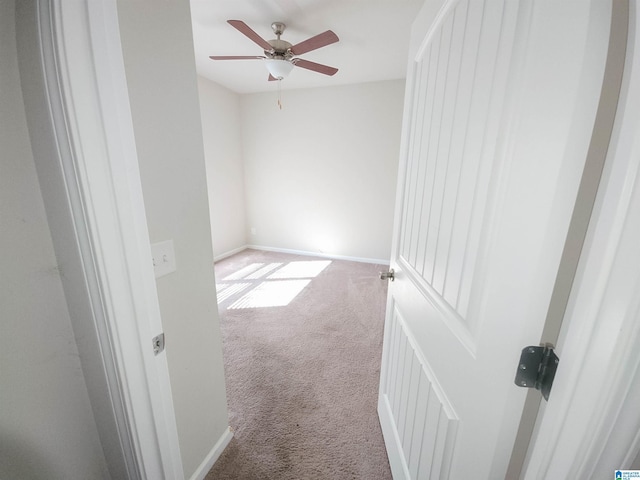 carpeted empty room featuring ceiling fan and baseboards