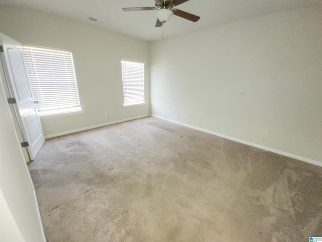 carpeted spare room featuring ceiling fan and baseboards