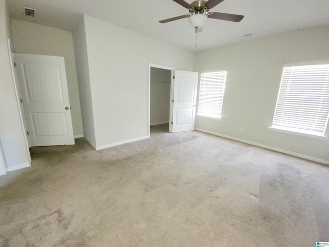 unfurnished bedroom with light carpet, baseboards, visible vents, and a walk in closet