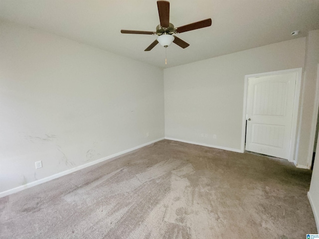 carpeted spare room with baseboards and a ceiling fan