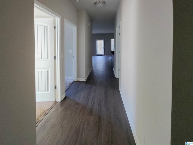 hallway with baseboards and dark wood-type flooring