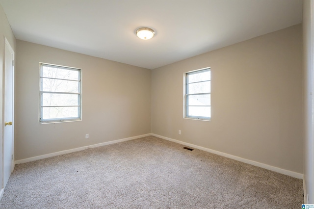 carpeted spare room featuring visible vents and baseboards