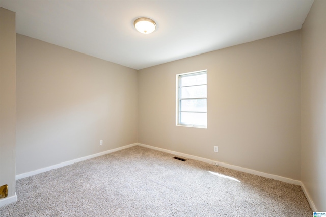 carpeted spare room featuring baseboards and visible vents