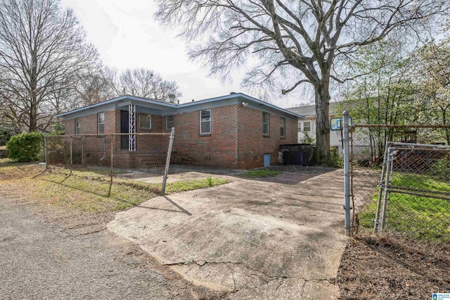 exterior space featuring concrete driveway, brick siding, fence, and a gate