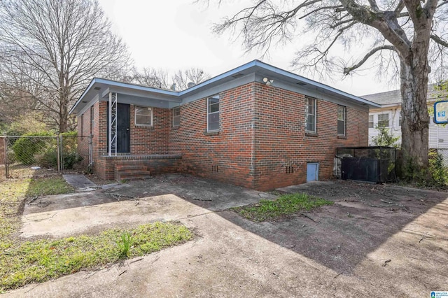 view of side of property featuring brick siding and fence