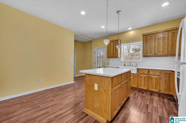 kitchen featuring dark wood-style floors, tasteful backsplash, a kitchen island, and a sink