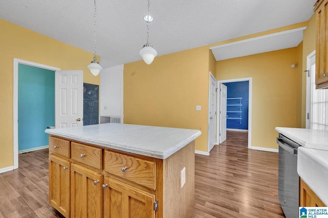 kitchen with light countertops, stainless steel dishwasher, and wood finished floors