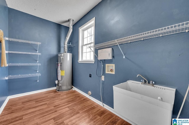 washroom with hookup for a washing machine, water heater, hookup for an electric dryer, wood finished floors, and laundry area