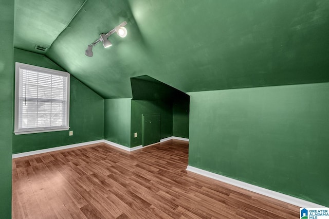 bonus room with visible vents, vaulted ceiling, baseboards, and wood finished floors