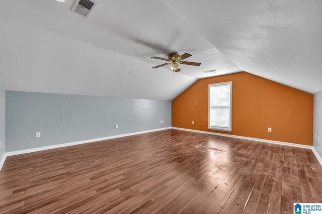 additional living space featuring baseboards, visible vents, vaulted ceiling, and wood finished floors