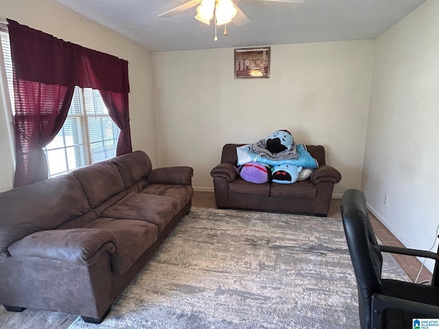 carpeted living room featuring a ceiling fan and baseboards