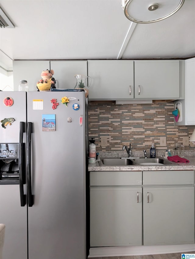 kitchen featuring stainless steel fridge, decorative backsplash, a sink, and light countertops