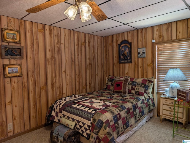 carpeted bedroom featuring ceiling fan and wood walls