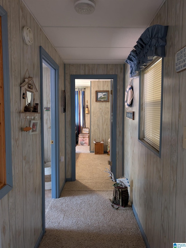 corridor with baseboards, carpet flooring, and wooden walls