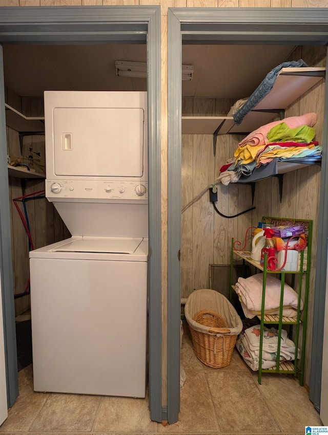 laundry room with laundry area, wooden walls, and stacked washer / dryer