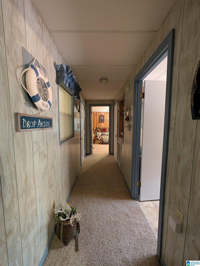 hallway featuring light carpet and wood walls