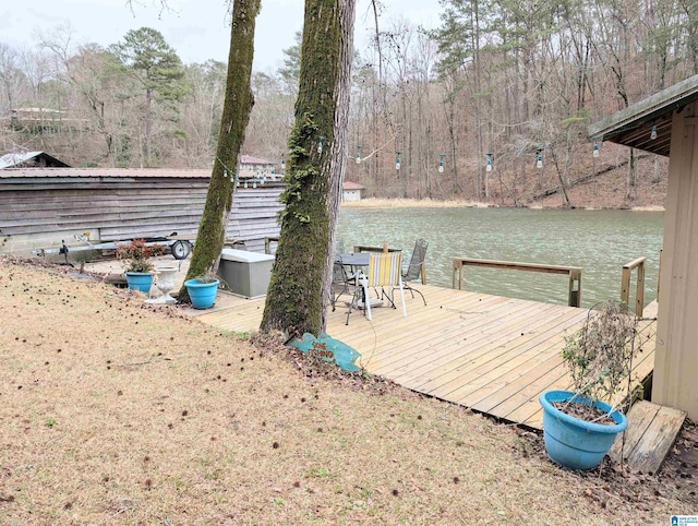 wooden deck with a dock, a water view, and a forest view