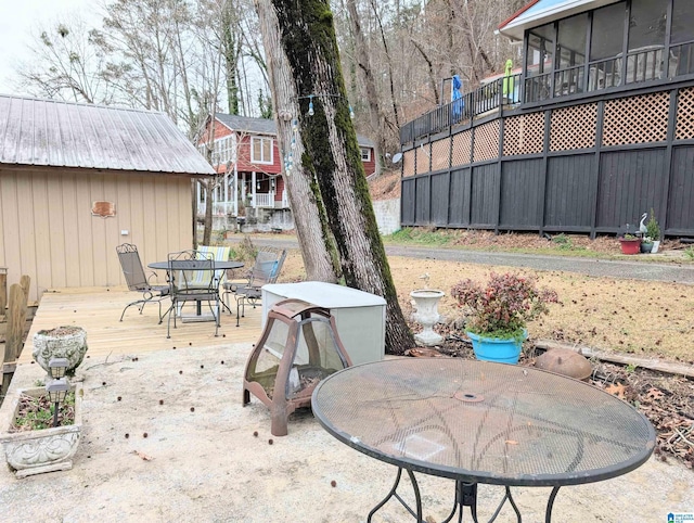 view of patio / terrace featuring outdoor dining area, a wooden deck, and a sunroom