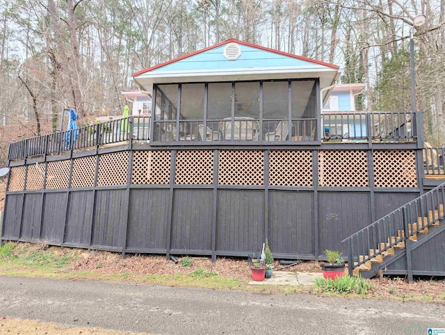 back of house featuring stairs, a deck, and a sunroom