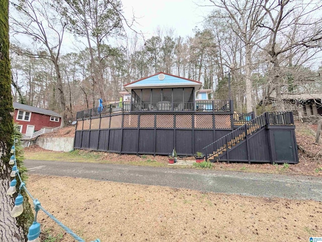 view of yard featuring a sunroom, a wooden deck, and stairs