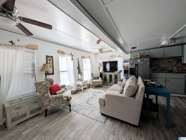 living area with a ceiling fan, visible vents, and wood finished floors