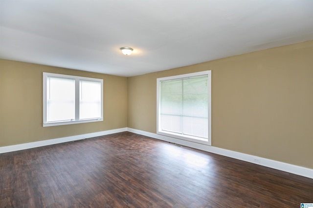 unfurnished room featuring baseboards, visible vents, and dark wood-style flooring