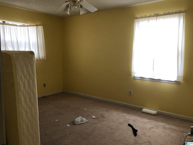 empty room featuring carpet, a healthy amount of sunlight, and ceiling fan