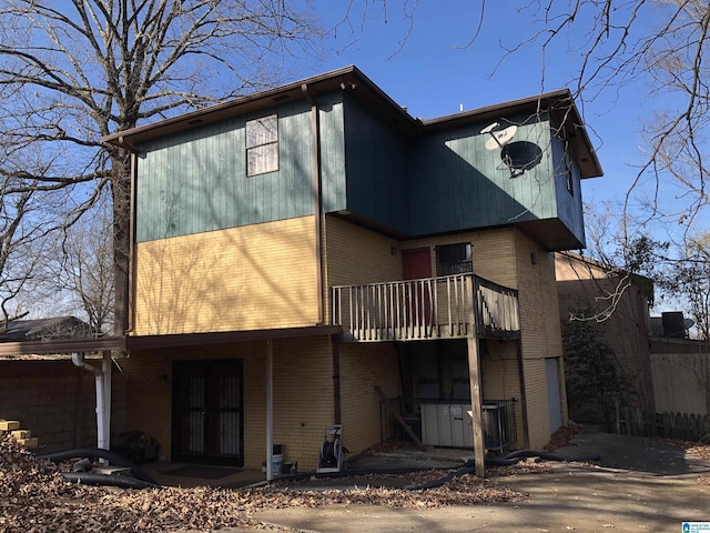 rear view of house featuring brick siding and a balcony