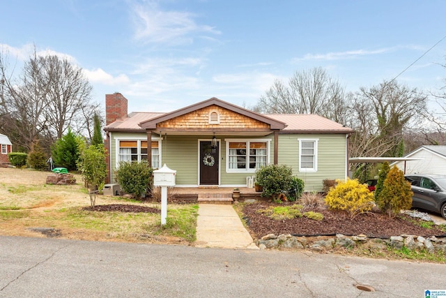 bungalow-style house featuring metal roof, a porch, and a chimney