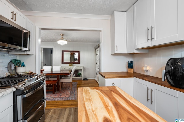 kitchen featuring wood finished floors, appliances with stainless steel finishes, backsplash, and wood counters