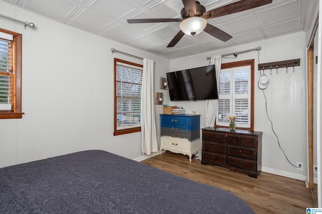 bedroom featuring ceiling fan, wood finished floors, and an ornate ceiling