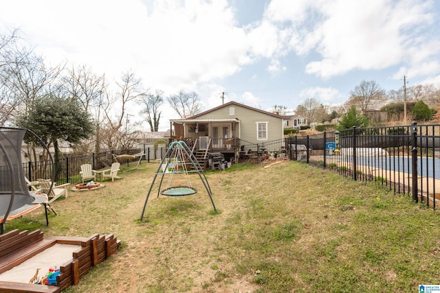 view of yard with a playground, a fenced backyard, a fire pit, a trampoline, and a swimming pool