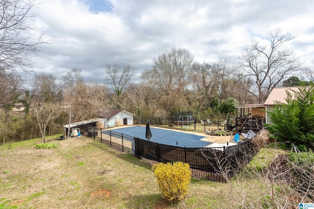 view of swimming pool featuring an outbuilding, a lawn, fence, and a fenced in pool