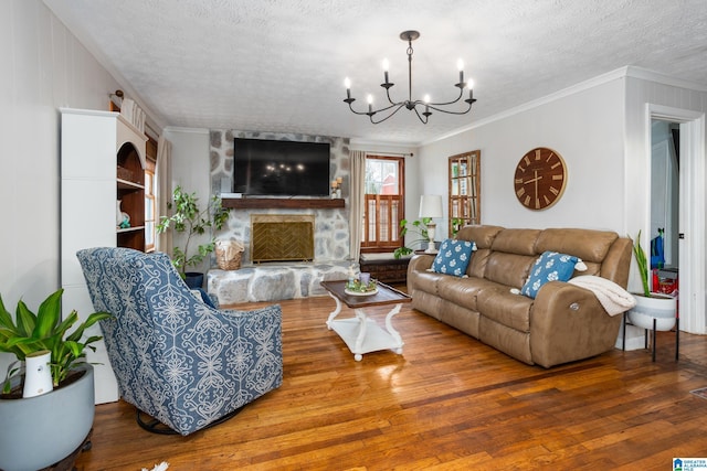 living room featuring a notable chandelier, ornamental molding, a stone fireplace, a textured ceiling, and wood finished floors