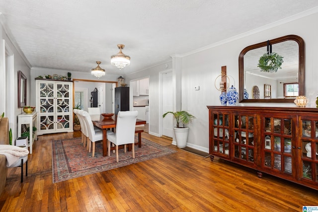 dining room with baseboards, hardwood / wood-style flooring, ornamental molding, a textured ceiling, and a notable chandelier