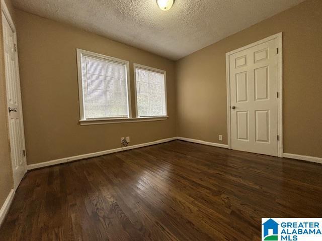 unfurnished bedroom featuring a textured ceiling, baseboards, and wood finished floors