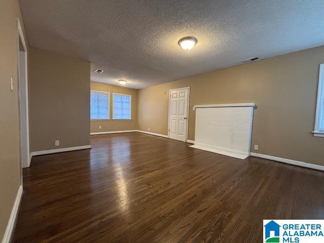 empty room with baseboards, visible vents, and wood finished floors