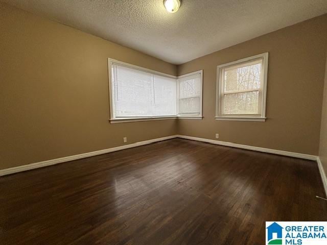 unfurnished room featuring a textured ceiling, baseboards, and dark wood-style flooring