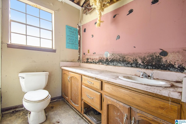 bathroom with toilet, vanity, and baseboards