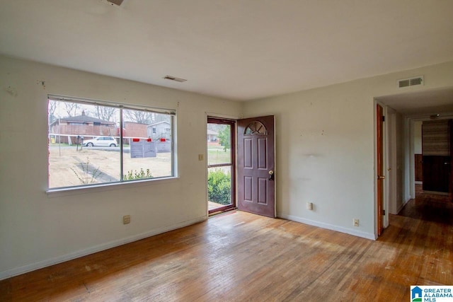 unfurnished room featuring baseboards, visible vents, and hardwood / wood-style floors