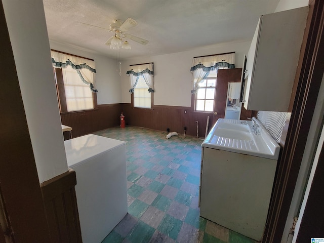 clothes washing area with a wainscoted wall, wood walls, a ceiling fan, tile patterned floors, and washer / dryer