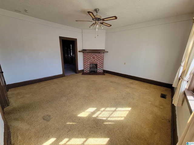 unfurnished living room with visible vents, baseboards, a ceiling fan, carpet flooring, and a brick fireplace