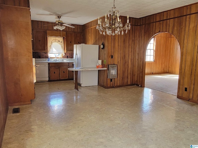 kitchen featuring arched walkways, white appliances, wood walls, light countertops, and heating unit