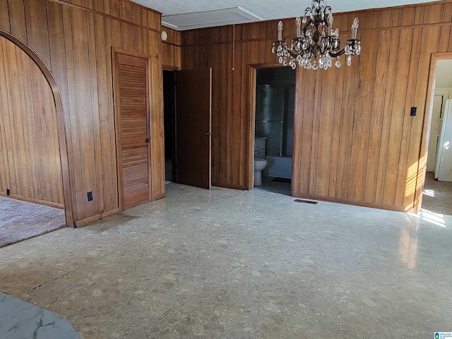 unfurnished dining area with visible vents, wood walls, and an inviting chandelier