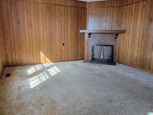 unfurnished living room with carpet, wooden walls, visible vents, and a fireplace