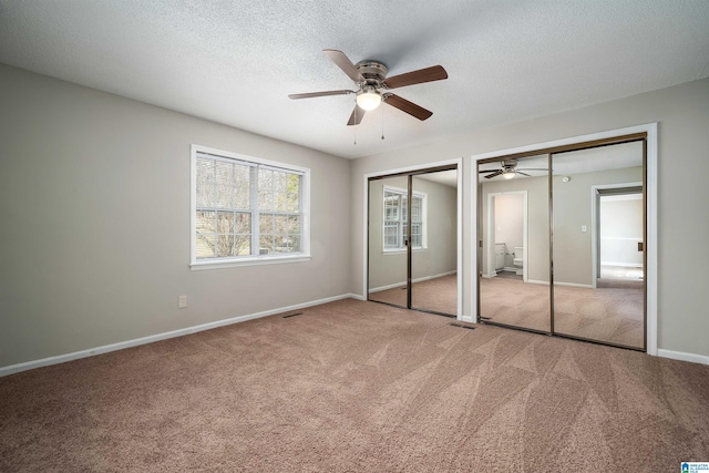 unfurnished bedroom featuring multiple closets, carpet floors, baseboards, and a textured ceiling