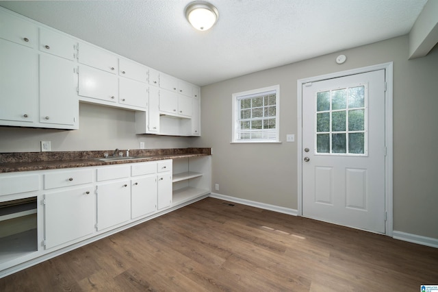 kitchen featuring dark wood-style floors, dark countertops, white cabinetry, a sink, and a textured ceiling