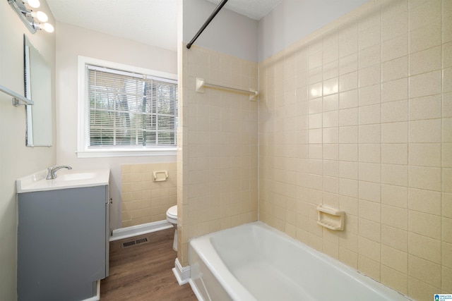 bathroom with visible vents, toilet, shower / tub combination, wood finished floors, and vanity