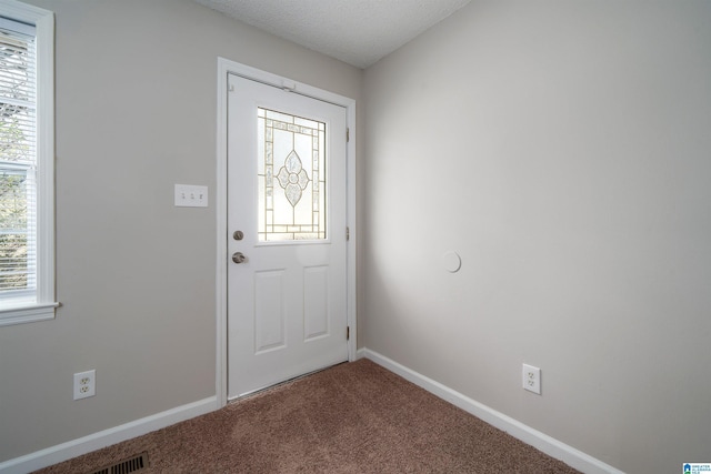 entryway featuring a textured ceiling, carpet floors, and baseboards