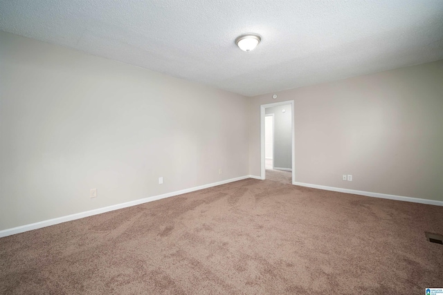 spare room with a textured ceiling, carpet, visible vents, and baseboards